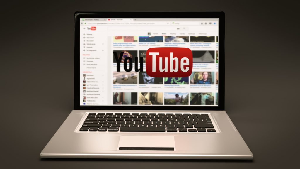 Bild på en uppfälld bärbar dator som står på ett bord. Youtubes förstasida syns.